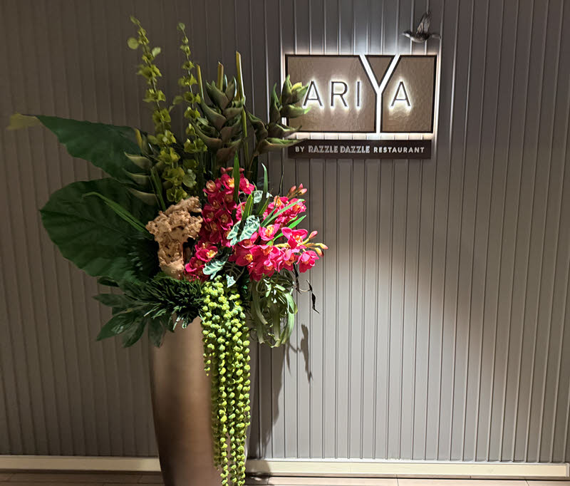 Flower pot with Ariya restaurant sign behind it